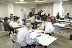 青色申告会会員が持参した確定申告の提出書類を点検する担当者