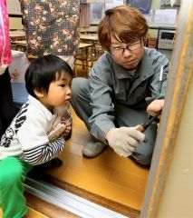 子供が見守る中、引き戸の立て付けを直す組合企業の社員