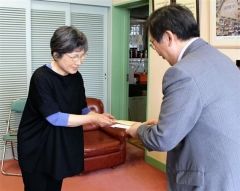 寄付金を須永校長に贈る山口多鶴子さん（左）
