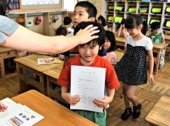 「１学期よく頑張りました」－。小学生となり成長した点を褒められながら初めての「あゆみ」を受け取る１年生（２４日午前１１時４０分ごろ、帯広つつじが丘小で、金野和彦撮影）
