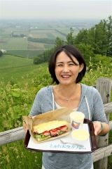 新嵐山からの景色を背景に芽室産にこだわったランチセットをPRする井澤実行委員長