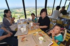 広大な畑の景色を眼下にサンドイッチを頬張る家族連れ（１７日午後０時ごろ、塩原真撮影）