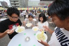 道内各地のご当地グルメや人気ラーメンが集結した会場で舌鼓を打つ来場者(8日午前11時20分、折原徹也撮影)