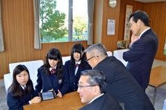 タブレットを使って西山村長らにフランスの成果を報告する高橋さんと菅さん、淡路さん（奥左から）