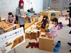 段ボールを使った滑り台など遊具を使って遊ぶ家族連れ