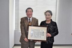 表彰状を手に笑顔を見せる金田さん。右は北海道生涯学習協会の中田和子副理事