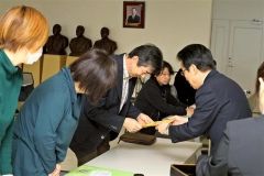 調印後の確認を終えた土江田会長（右）から協定書を受け取る家族