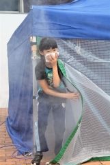 煙が充満するテントからハンカチで口をふさいで避難する子供