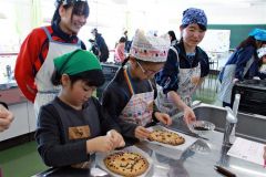 指導を受け、クッキーにチョコペンでデコレーションする子どもたち