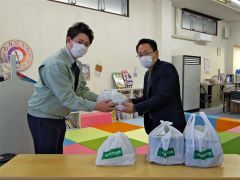 伊豆倉組の伊豆倉鈴雄業務室長（写真左）から、きずなの森・きずなの星の池田管理者に弁当が手渡された。