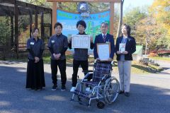 柚原園長（右から２人目）に車いすを贈呈した佐藤主任（中央）