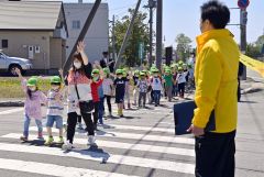 手を上げて横断歩道を渡る子どもたち（小山田竜士撮影）