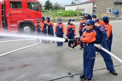 隊員のアドバイスを受けて放水作業を体験する女子メンバー