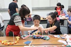 講師（左）のアドバイスをもらってヘビのおもちゃ作りに挑戦する子どもたち