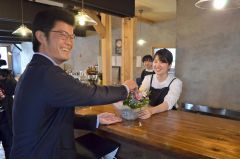 来店者から開店祝いのブーケを受け取る美月店長（右）