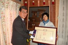 佐々木町長（左）から、叙位と特別叙勲を伝達される高橋前町長の妻の照子さん