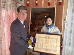 佐々木町長（左）から、叙位と特別叙勲を伝達される高橋前町長の妻の照子さん