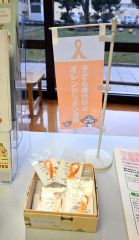 児童虐待防止を呼び掛ける「オレンジリボン運動」のリボンを無料配布している