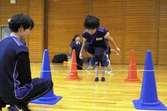 ゴムひもを跳ぶ動作では、胸と膝を近づけるコツを伝える