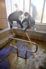 あさひ苑の浴槽にモール温泉を注ぎ込む青年部員ら（左が山崎部長）