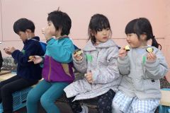 高校生と一緒に植えたサツマイモを食べる園児たち