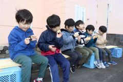 高校生と一緒に植えたサツマイモを食べる園児たち