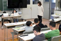 藤原さん（右）のアドバイスを受け、ニュース原稿読みに挑戦する子どもたち