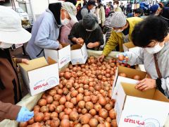 タマネギの詰め放題で品定めする来場者


