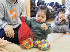 ペットボトルのキャップで作成した音の鳴るおもちゃに興味津々の子ども