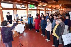 山内代表（右）の指揮で、「赤い山青い山白い山」を歌う「あかねぐもの会」メンバー
