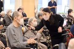 社会福祉施設の利用者にマイクを向けながら一緒に歌う中村仁美さん(中央)