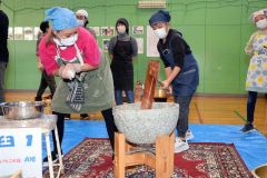 保護者と協力して餅をつく児童たち
