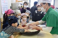 そば粉に水を回して入れる作業を体験する参加者ら