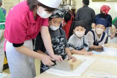 包丁でそばを切っていく作業を体験する参加者
