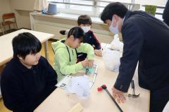 高校生（右端）に教わりながら作業する児童たち