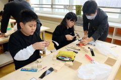 高校生（右端）に教わりながら作業する児童たち