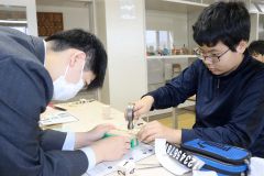 高校生（左）に教えてもらいながら作業する児童