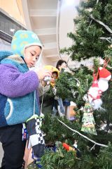 雪だるまやサンタなどのオーナメントを飾る園児ら