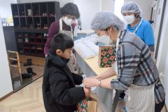 お弁当を手渡しする藤原代表（右）
　