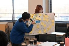 模造紙にまとめたアイディアを発表する学生ら