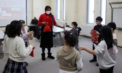 輪になってブリタニ―さん（中央）と一緒にプレゼント交換する子どもたち