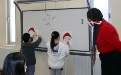 ブリタニ―さん（右）とサンタクロースの福笑いを楽しむ子どもら