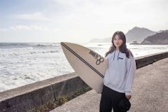 ホーム・ビーチのフンベ海岸をバックに。「自然の中で楽しめるのがサーフィンの魅力」という（撮影・石原秀樹通信員）
