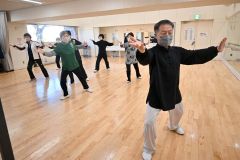 原田さん（右）の指導の下、ゆっくりとした太極拳の動きで心身の健康を目指す会員たち