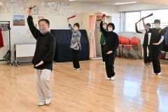 扇を使った太極拳の動きに取り組む会員たち
