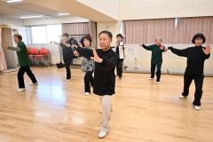 原田さん（中央）の指導の下、ゆっくりとした太極拳の動きで心身の健康を目指す会員たち