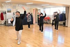 扇を使った太極拳の動きに取り組む会員たち
