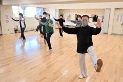 原田さん（右）の指導の下、ゆっくりとした太極拳の動きで心身の健康を目指す会員たち