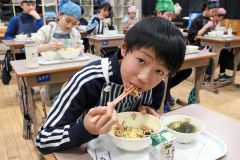 高校生考案の給食メニューを味わう児童