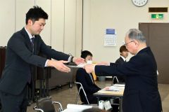 有塚組合長から激励状を受け取る新規就農者（左）